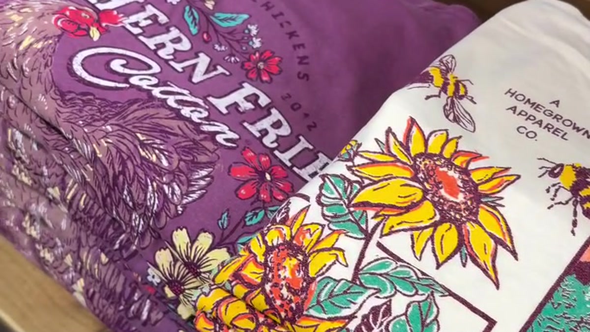 Colorful fabric with bright sunflower and floral print on white panel, text and bees visible on the right edge.
