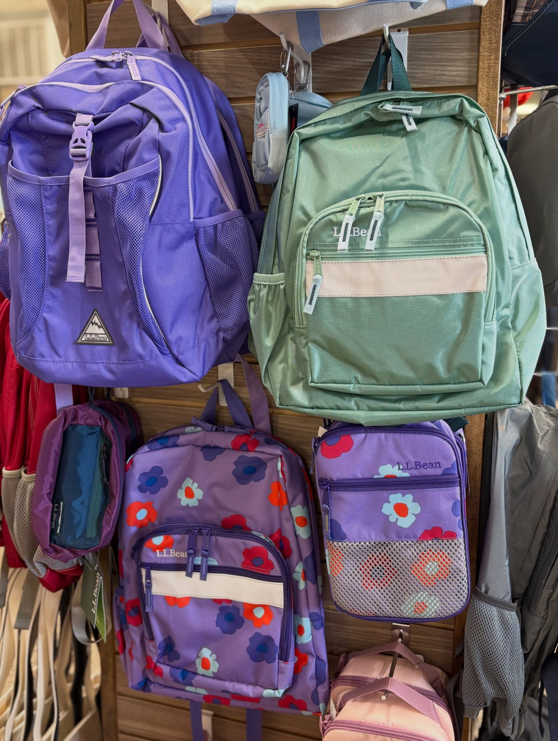 Purple LL Bean backpack with mesh side pocket hanging on a wooden rack display.