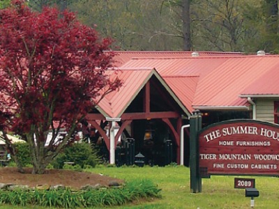 Red-roofed building with a wooden sign reading 'The Summer House' in a landscaped front yard.