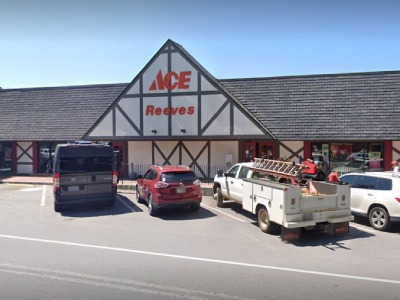 Ace Hardware store with Tudor-style front, 'ACE Reeves' sign, and several cars parked in front.