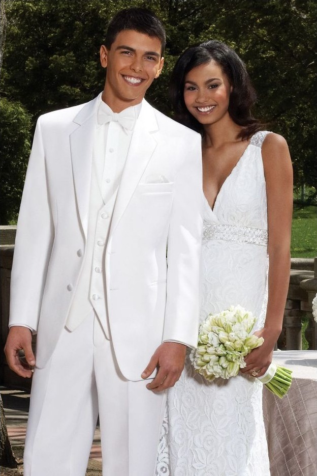 Reeves Tuxedo Rental (White Troy Tuxedo) - Reeves 1928 Bride and groom in white wedding attire posing together outdoors, the bride holding a bouquet of white flowers.