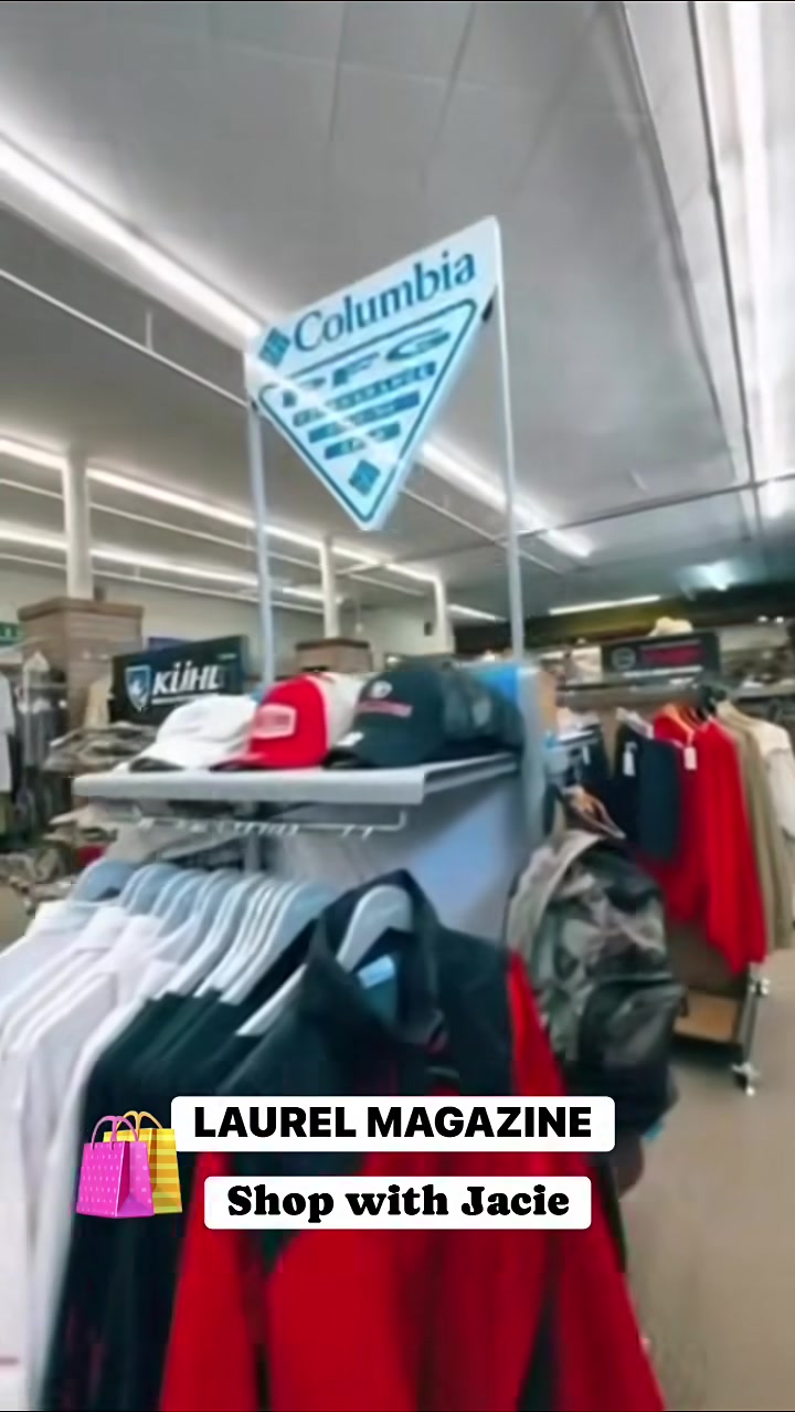 Inside a clothing store with racks of shirts and a hanging blue Columbia sign above.